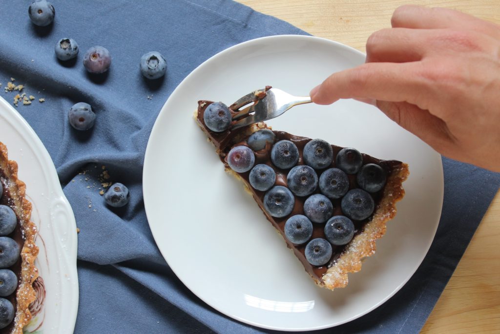 fetta di crostata alle nocciole con mirtilli e cioccolato